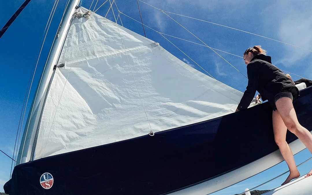 Woman adjusting the sail as it is raised up the mast