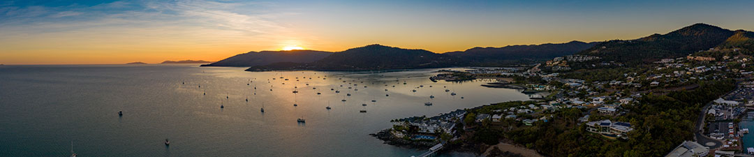 Sunset over the water with mountains and boats