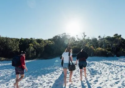 People walking on the beach towards the sun