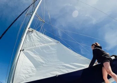 Woman adjusting the sail as it is raised up the mast